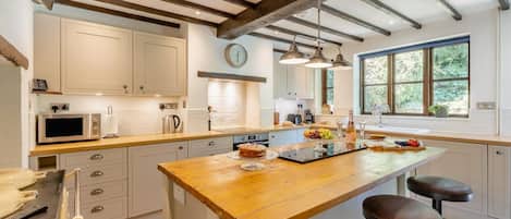 A modern kitchen with a wooden island, stainless steel appliances, and a large window providing natural light.