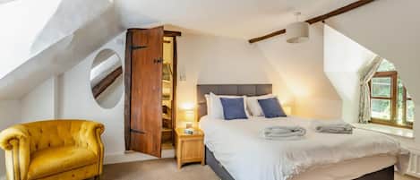 A bedroom with a bed, a chair, a nightstand, and a window.