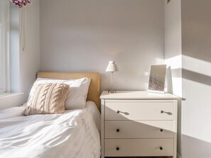 Ein Schlafzimmer mit einem Bett, einem Nachttisch, einer Lampe und einem Bilderrahmen.