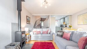 A modern living room with a fireplace, a grey sofa, a red rug, and a staircase leading to an upper floor. - 2 Bed in Ambleside (oc-lr114) (Chapel Stile)