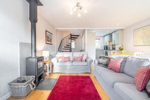 Ein modernes Wohnzimmer mit Kamin, einem grauen Sofa, einem roten Teppich und einer Treppe, die zu einer oberen Etage führt.