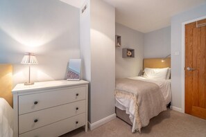 A bedroom with a bed, bedside table, lamp, and a small shelf with decorative items. - 2 Bed in Ambleside (oc-lr114) (Chapel Stile)