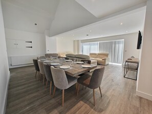 A modern dining area with a wooden table set for six, surrounded by grey upholstered chairs. - 5 Bed in Llandderfel (oc-b45562) (Llandderfel)