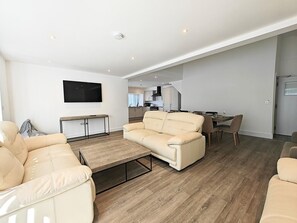 A modern living room with a sofa, a coffee table, and a TV mounted on the wall.