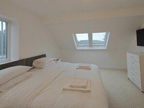 Ein Schlafzimmer mit einem Bett, einem Schminktisch, einem Fenster und einem Fernseher.