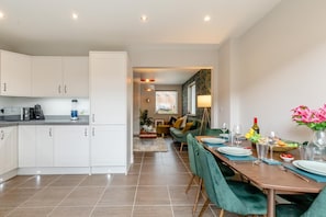 Eine moderne Küche mit weißen Schränken und einem Essbereich mit einem Holztisch, gedeckt für vier Personen.