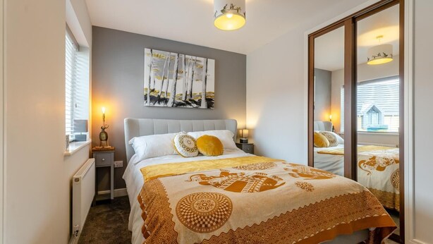 Un dormitorio con cama, mesitas de noche, un espejo y una ventana.