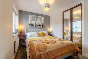 Ein Schlafzimmer mit Bett, Nachttischen, einem Spiegel und einem Fenster.