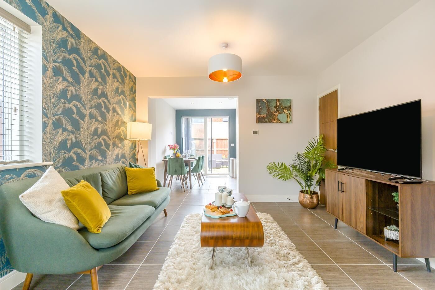 Un salon comprenant un canapé, une table basse, un téléviseur et un coin repas avec des chaises et une table.