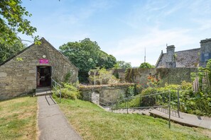A stone building with a staircase leading to a bridge over a water channel. - 4 Bed in Newquay (oc-s45403) (Black Cross)