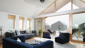A modern living room with a sofa set, a coffee table, and a dining area. - 3 Bed in Mawgan Porth (oc-b599246) (Saint Eval)