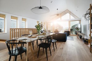 A modern dining area with a glass table, black chairs, and a wooden partition. - 3 Bed in Mawgan Porth (oc-b599246) (Saint Eval)