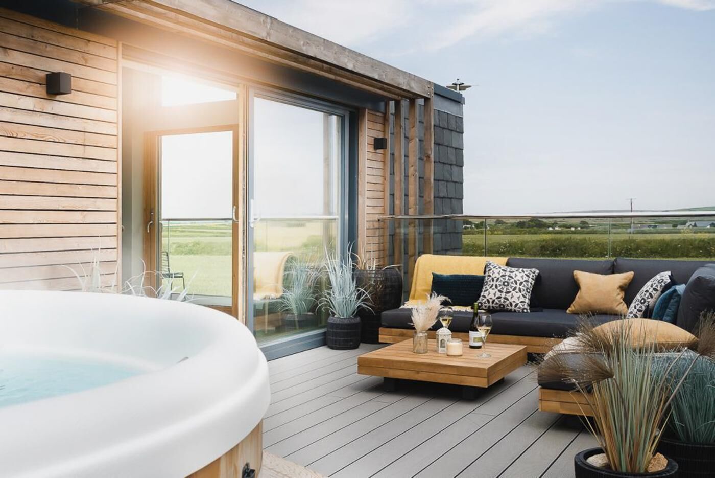 Un área de estar exterior moderna con una bañera de hidromasaje, un sofá y una mesa de centro.