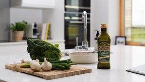 A kitchen counter with fresh vegetables, a bottle of olive oil, and a white ceramic pot. - 3 Bed in Mawgan Porth (oc-b599246) (Saint Eval)