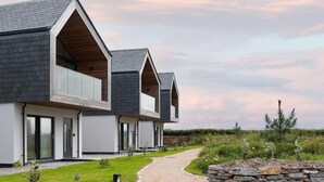 A modern two-story house with a gravel driveway and a stone wall. - 3 Bed in Mawgan Porth (oc-b599246) (Saint Eval)