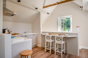 A kitchen with a central island, white cabinetry, a window with a view, and a wooden stool. - 1 Bed in Bournheath (oc-h45428) (Catshill)