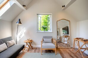 A cozy room with a grey sofa, a wooden chair, a small table with a lamp, a large mirror, and a chessboard. - 1 Bed in Bournheath (oc-h45428) (Catshill)