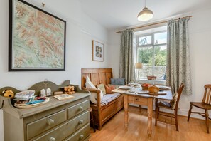 Une pièce confortable avec un lit en bois, une table à manger avec des chaises, une commode et une grande fenêtre avec des rideaux.
