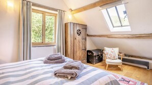 Ein Schlafzimmer mit einem Bett, einem Sessel, einem Kleiderschrank und einem Fenster.
