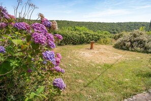 Un jardín con flores de hortensia y una maceta de piedra.