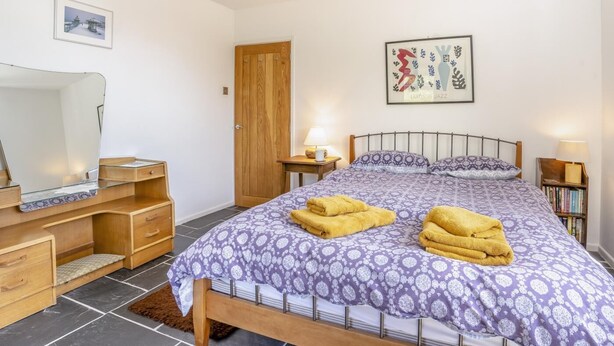A bedroom with a bed, bedside tables, a desk, a mirror, and a door. - 3 Bed in Llwyn Du (oc-t44969) (Abergavenny)
