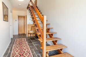 Eine Holztreppe mit Handlauf, die zu einer Zwischenebene führt.