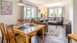 A well-lit living room with a dining area, a sofa set, and a fireplace. - 3 Bed in Llwyn Du (oc-t44969) (Abergavenny)