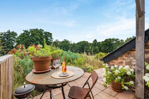 An outdoor patio with a round table, chairs, a wine bottle, and potted plants. - 1 Bed in St. Weonards (oc-t30416) (Saint Weonards)