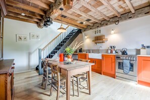 Eine Küche mit Holzbalken, einer Treppe und einem Essbereich mit Tisch und Stühlen.