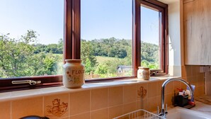 A kitchen with a view of a green landscape through large windows, a kettle, a sink, and two jars labeled 'FLOUR' and 'SUGAR'. - 3 Bed in Croscombe (oc-c45357) (Croscombe)