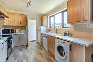 A modern kitchen with wooden cabinets, a built-in oven, microwave, and dishwasher. - 3 Bed in Croscombe (oc-c45357) (Croscombe)