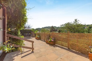 Une terrasse avec une clôture en bois, des meubles d’extérieur et des plantes en pot.