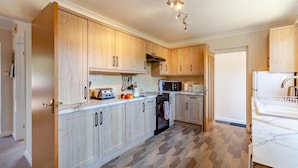 A modern kitchen with wooden cabinets, a built-in oven, a microwave, and a sink. - 3 Bed in Croscombe (oc-c45357) (Croscombe)