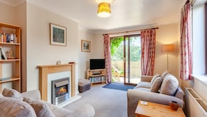 A living room with a fireplace, a sofa, a television, and a bookshelf. - 3 Bed in Croscombe (oc-c45357) (Croscombe)