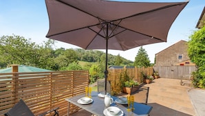 An outdoor patio with a table set for dining, a large umbrella, and a wooden fence. - 3 Bed in Croscombe (oc-c45357) (Croscombe)