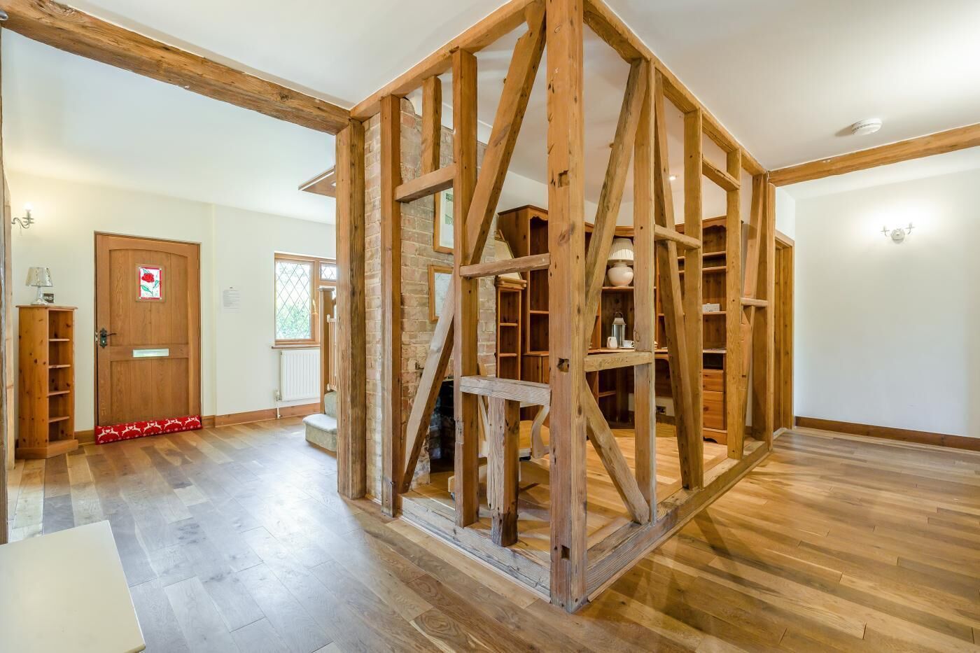 Una habitación con vigas de madera a la vista, una chimenea y una puerta de madera con una decoración de flor roja.