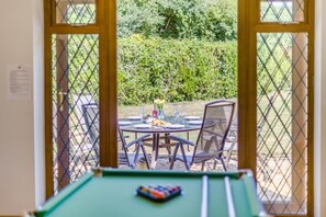 An indoor pool table with a view of an outdoor dining area through a window. - 6 Bed in West Wickham (oc-w45418) (Horseheath)
