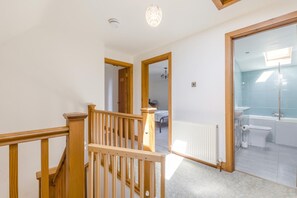 A staircase leading to a bedroom with a bed, a radiator, and a bathroom with a toilet and bathtub. - 6 Bed in West Wickham (oc-w45418) (Horseheath)