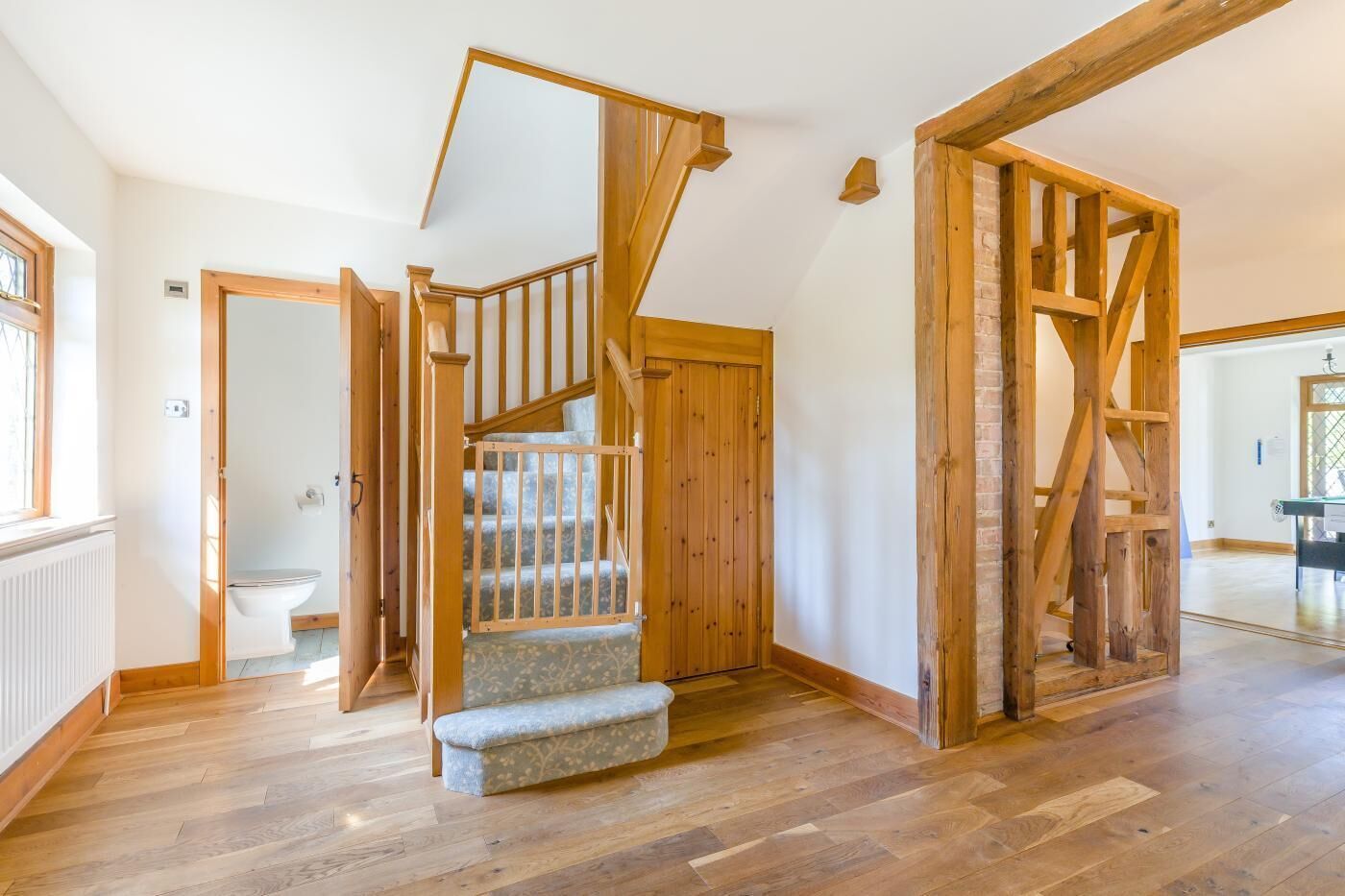 Una habitación amplia con escalera de madera, baño a la vista y zona de comedor.