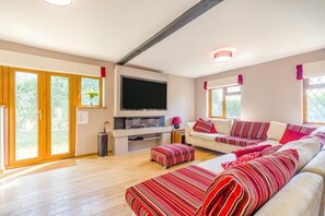 A modern living room with a flat-screen TV, a sofa set, and a wooden floor. - 6 Bed in West Wickham (oc-w45418) (Horseheath)