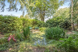 Ein Garten mit Teich, verschiedenen Pflanzen und zwei Flamingos.
