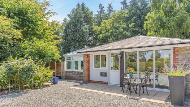 A house with a covered patio, a brick exterior, and a gravel driveway. - 1 Bed in Combe (oc-g45502) (Combe)