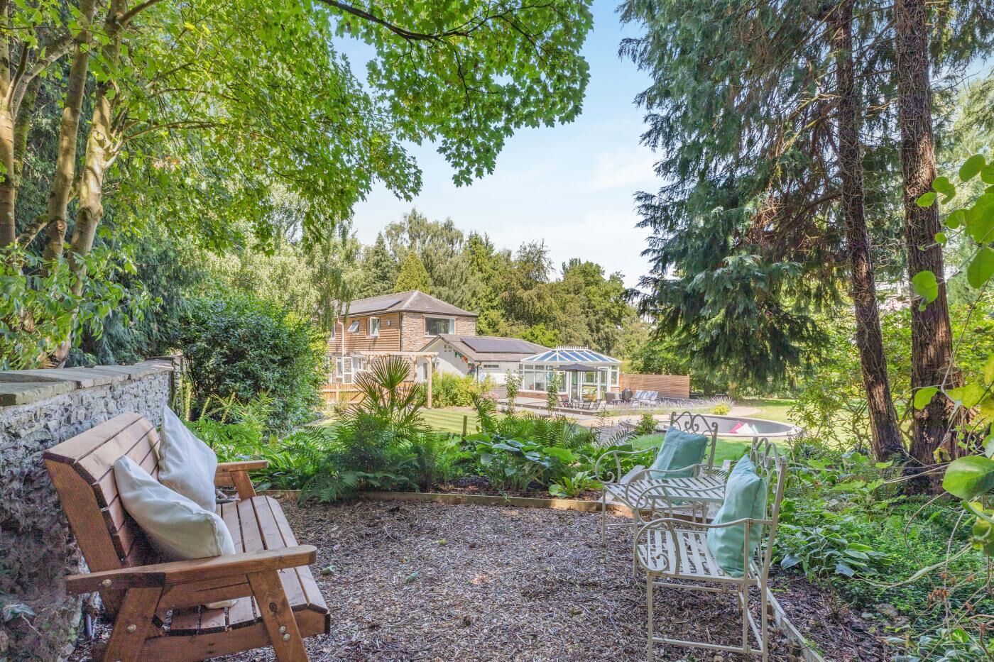 Une maison dotée d’un patio, d’un banc en bois et d’une chaise en métal.