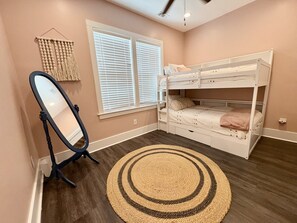 A room with a bunk bed, a standing mirror, and a circular rug. - Sound view with Private Saltwater Pool - A Tad Salty (Emerald Isle)