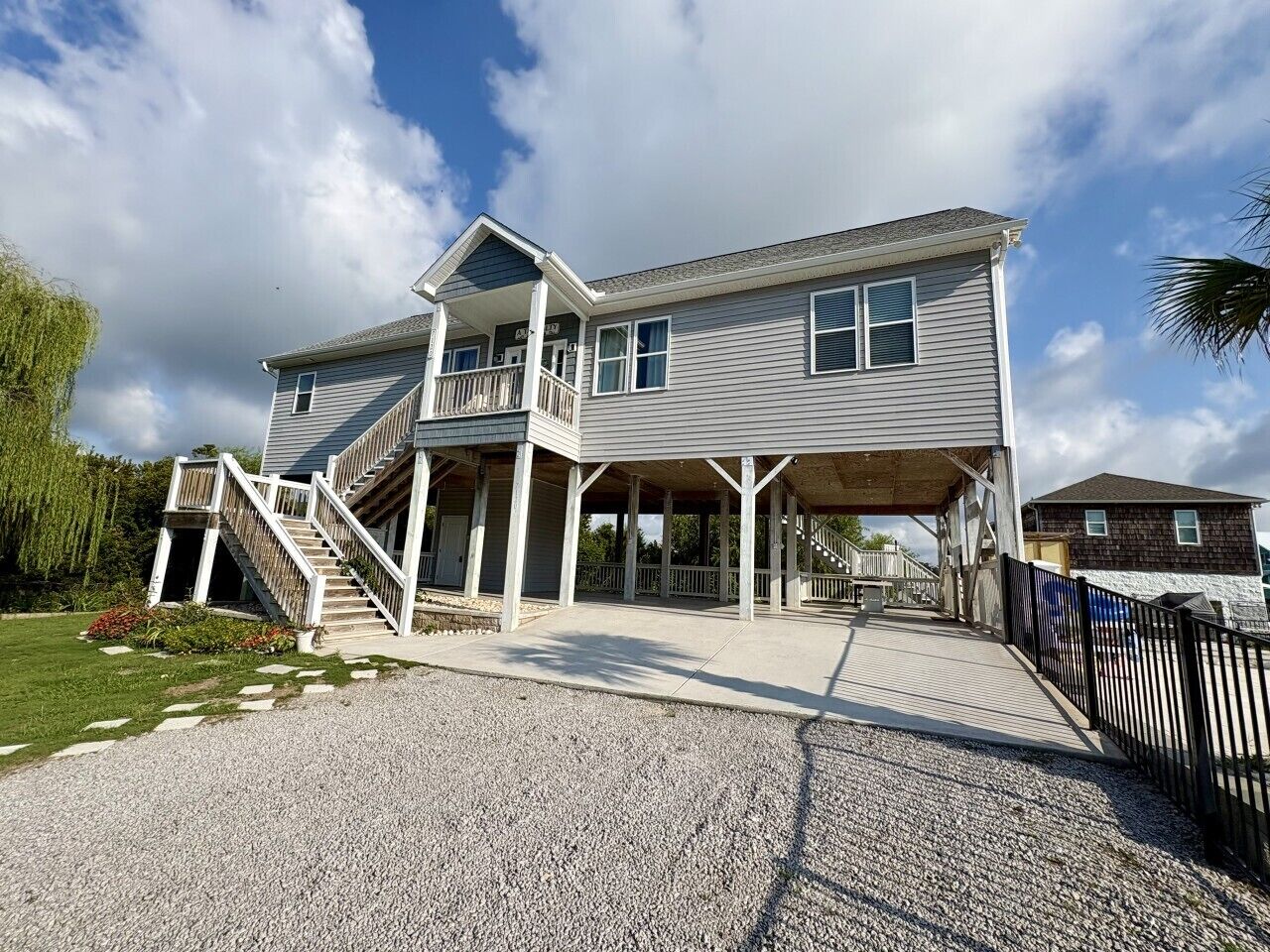 A two-story house with a covered porch, a staircase, and a driveway.