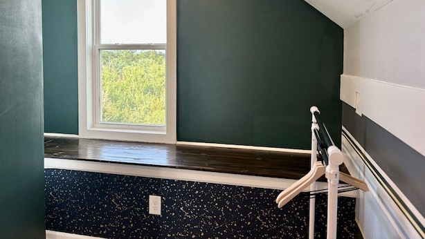 Um quarto com janela, piso de madeira e corrimão branco.