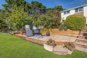 Ein gepflegter Garten mit einer Terrasse, Sitzgelegenheiten im Freien und einer Vielfalt an Pflanzen.