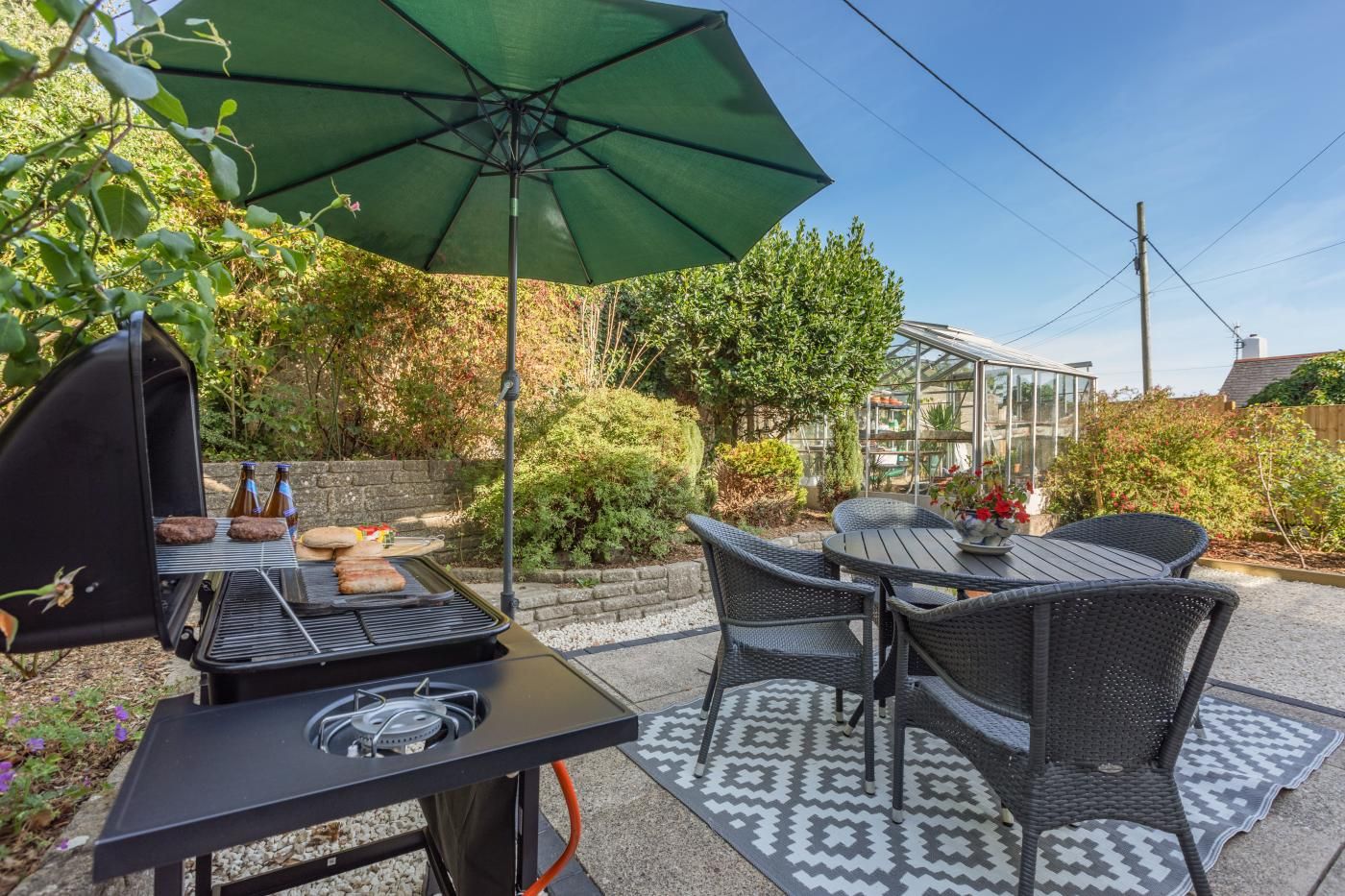 An outdoor patio with a grill, dining table, and chairs.