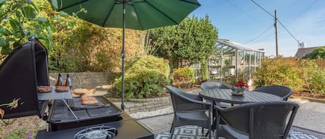 An outdoor patio with a grill, dining table, and chairs.