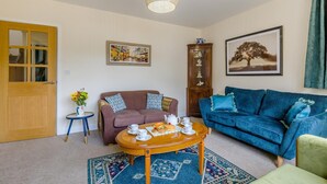 A living room with a brown sofa, a blue sofa, a wooden coffee table, and a patterned rug. - 2 Bed in Heacham (oc-l44862) (Heacham)